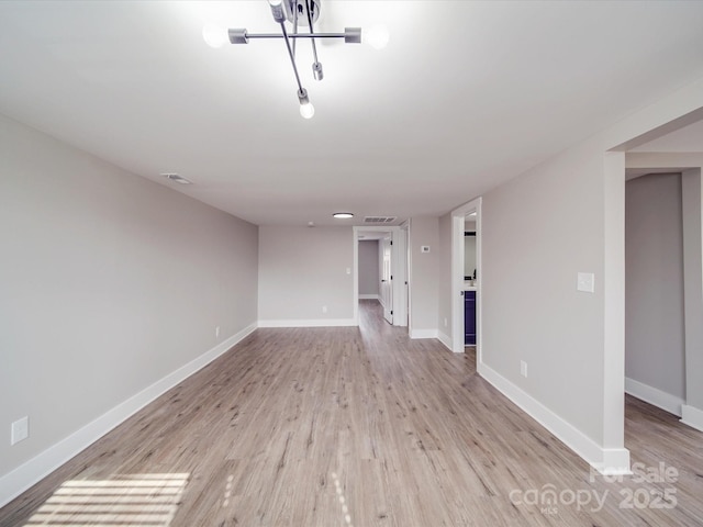 spare room with light wood finished floors, visible vents, and baseboards