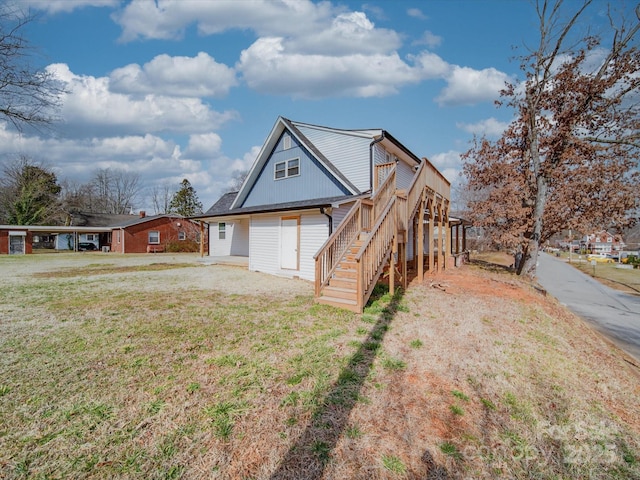 exterior space featuring stairs, a deck, and a front yard