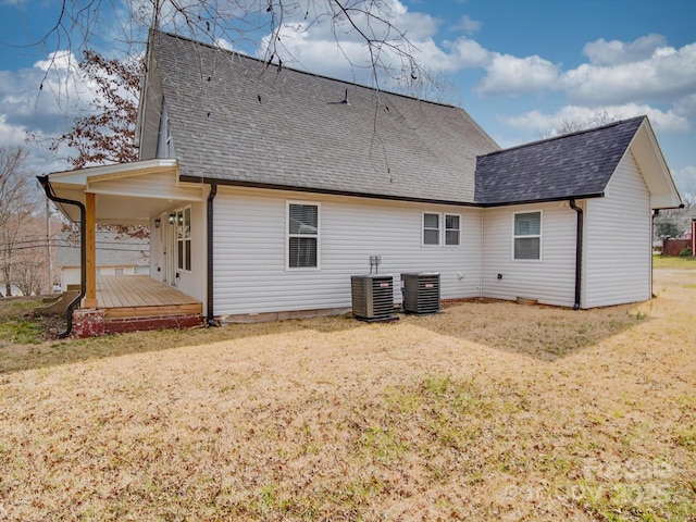 rear view of house featuring a shingled roof, a lawn, and central air condition unit