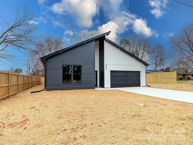 view of home's exterior with driveway, an attached garage, and fence