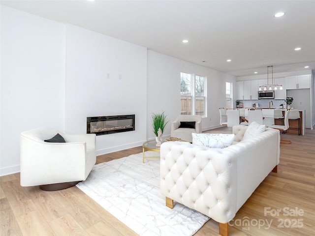 living room featuring light wood finished floors, a glass covered fireplace, and recessed lighting