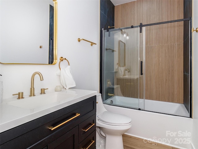 full bath with toilet, bath / shower combo with glass door, wood finished floors, and vanity