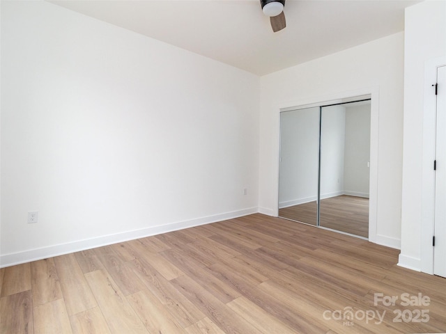 unfurnished bedroom featuring a closet, light wood-style flooring, and baseboards