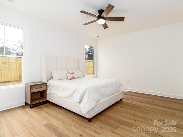 bedroom with light wood-type flooring, ceiling fan, and baseboards