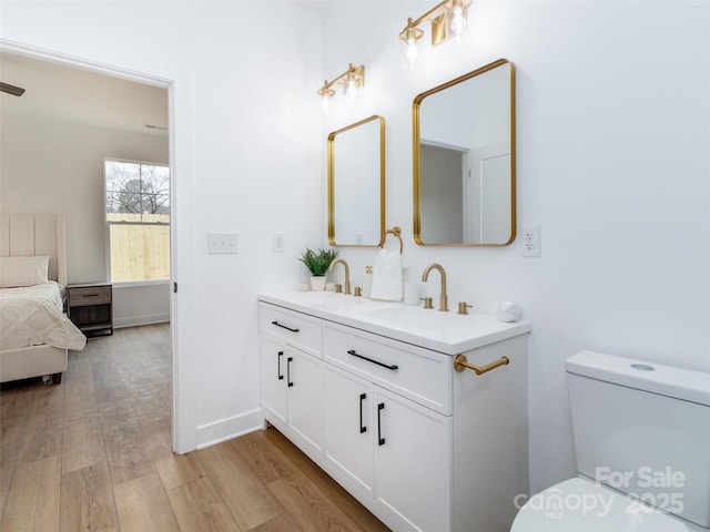 full bath featuring double vanity, a sink, toilet, and wood finished floors