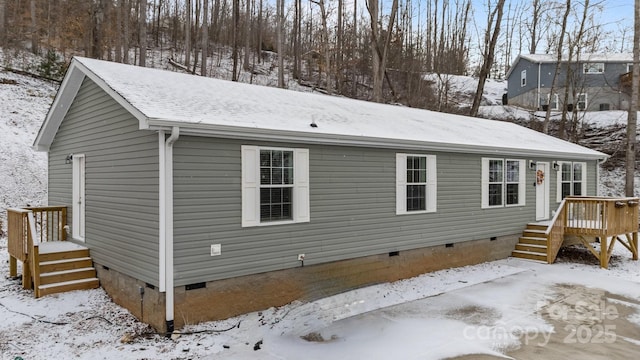 snow covered back of property featuring crawl space and roof with shingles