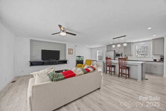 living room with light wood finished floors, recessed lighting, visible vents, a ceiling fan, and baseboards