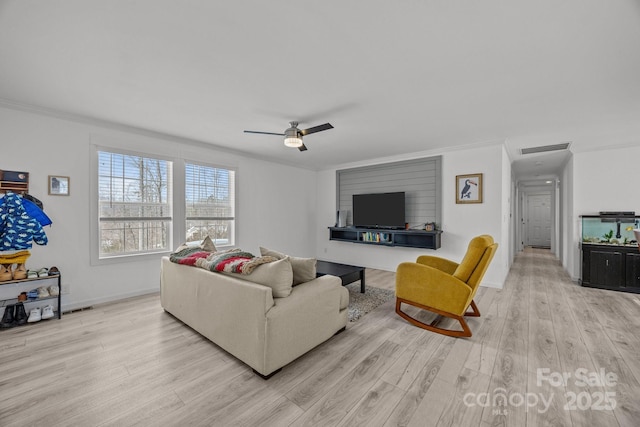 living area with crown molding, light wood finished floors, visible vents, ceiling fan, and baseboards