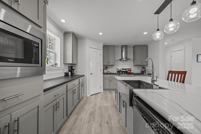 kitchen with appliances with stainless steel finishes, gray cabinetry, decorative light fixtures, and wall chimney exhaust hood