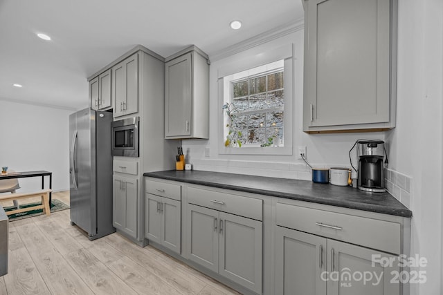 kitchen with recessed lighting, appliances with stainless steel finishes, gray cabinets, light wood finished floors, and dark countertops