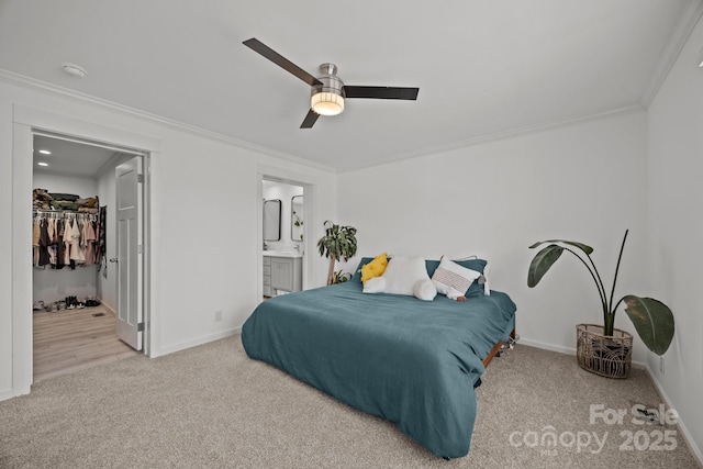 bedroom featuring crown molding, light colored carpet, ceiling fan, ensuite bath, and baseboards