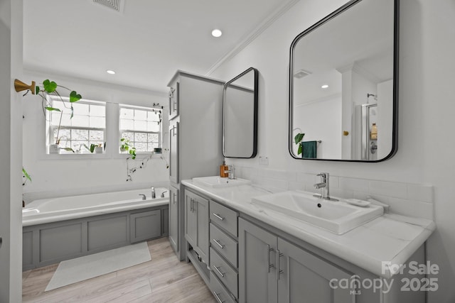 bathroom with double vanity, wood finished floors, a sink, and a bath