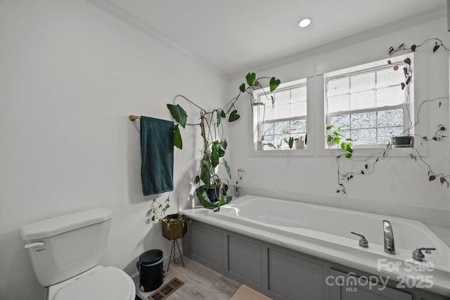 bathroom featuring ornamental molding, visible vents, toilet, and a bath