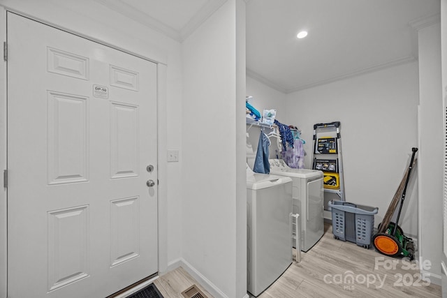 washroom featuring laundry area, baseboards, washer and clothes dryer, ornamental molding, and light wood-type flooring