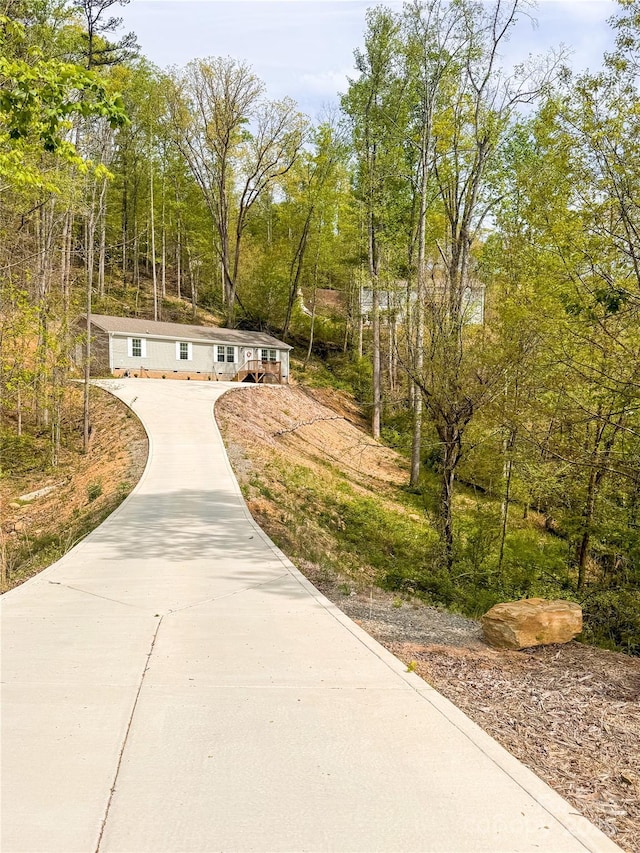 surrounding community with driveway and a wooded view