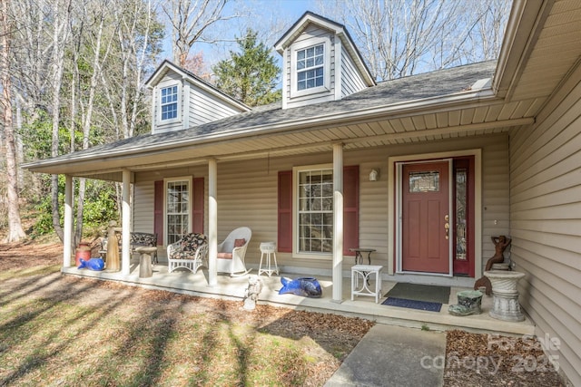 entrance to property featuring covered porch and roof with shingles