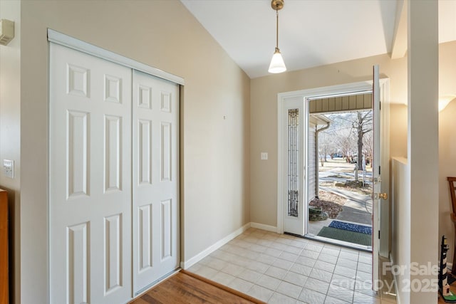 foyer entrance featuring vaulted ceiling and baseboards