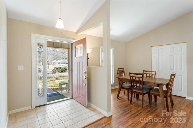 foyer entrance featuring lofted ceiling, light wood finished floors, and baseboards