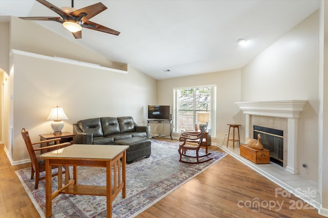 living area with light wood finished floors, baseboards, a tile fireplace, ceiling fan, and vaulted ceiling