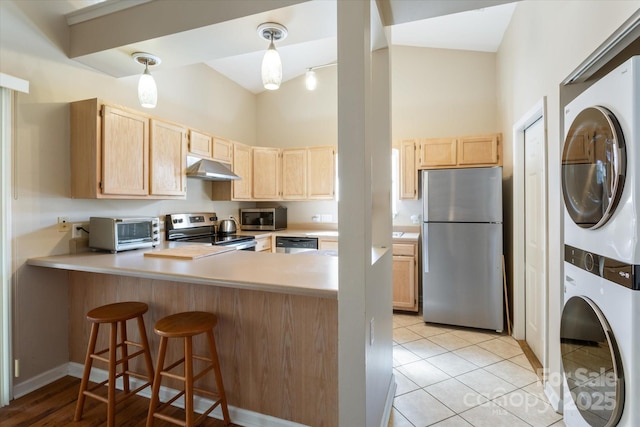 kitchen with stacked washer and dryer, appliances with stainless steel finishes, decorative light fixtures, light countertops, and light brown cabinets