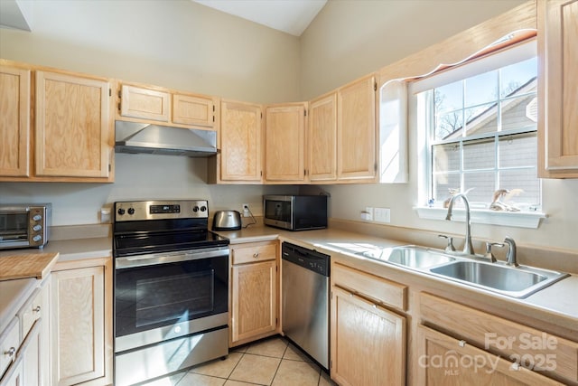 kitchen featuring appliances with stainless steel finishes, light countertops, under cabinet range hood, light brown cabinets, and a sink