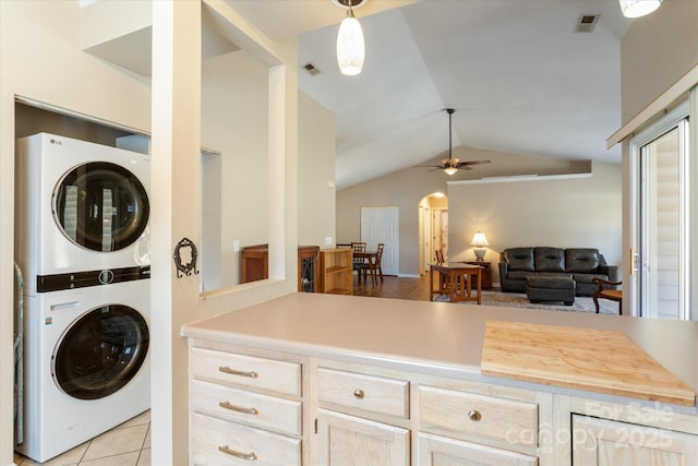 clothes washing area with light tile patterned floors, stacked washer and dryer, laundry area, visible vents, and a ceiling fan