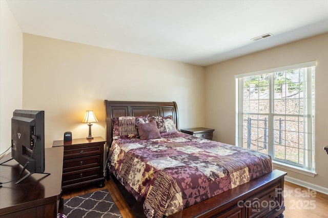 bedroom with wood finished floors, visible vents, and multiple windows