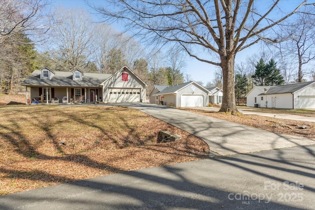 view of front of property with covered porch, concrete driveway, an attached garage, and a front yard