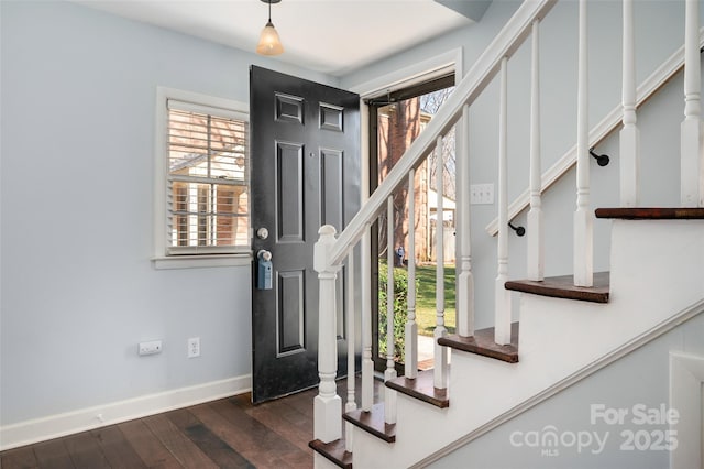 foyer entrance featuring dark wood-type flooring, baseboards, and stairs