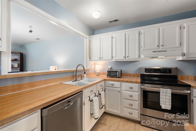 kitchen with light tile patterned floors, appliances with stainless steel finishes, under cabinet range hood, white cabinetry, and a sink