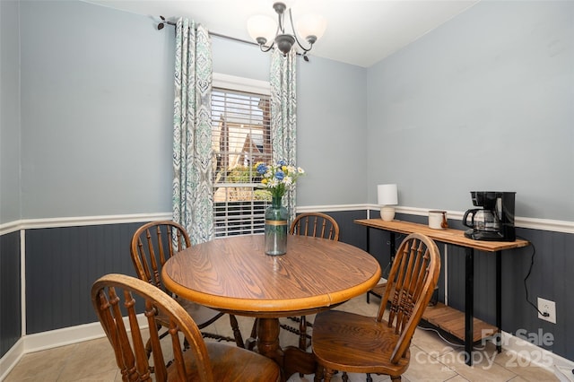 dining space featuring a chandelier, a wainscoted wall, and light tile patterned flooring