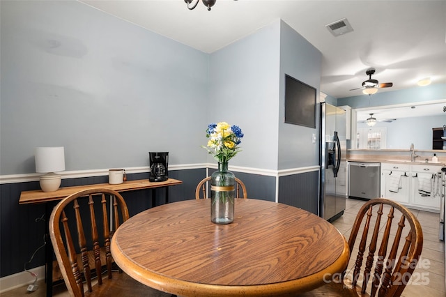 dining space featuring a wainscoted wall, visible vents, and light tile patterned flooring