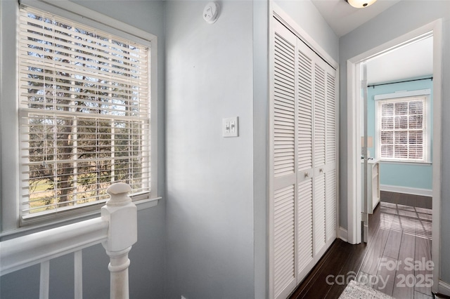 hallway featuring dark wood finished floors and baseboards