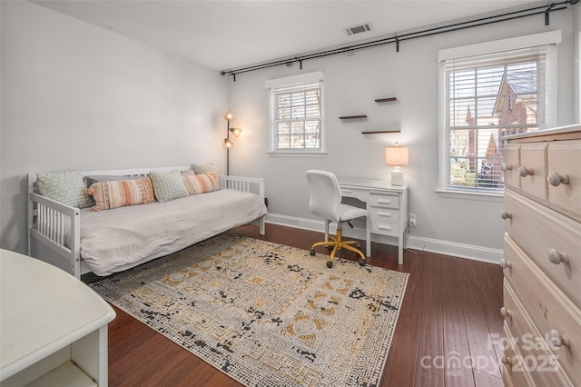 home office with baseboards, visible vents, and wood finished floors