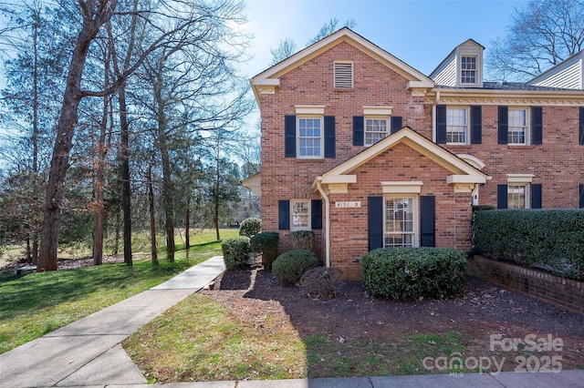 colonial home with a front yard and brick siding