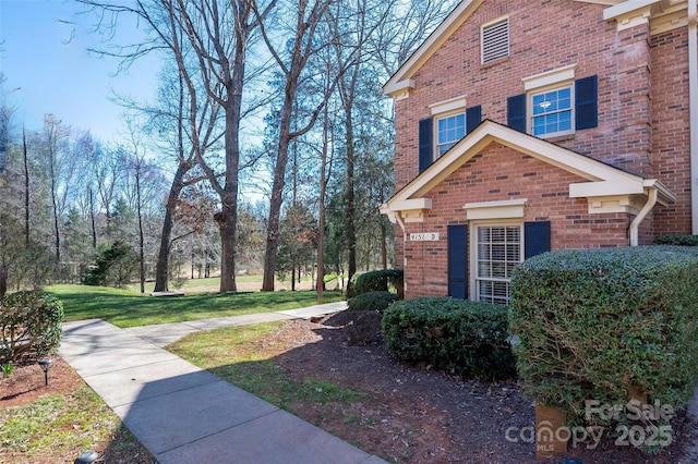 view of property exterior featuring a lawn and brick siding