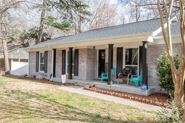 exterior space featuring a porch, a front lawn, and brick siding