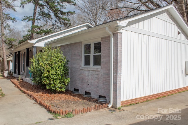 view of side of home with crawl space and brick siding