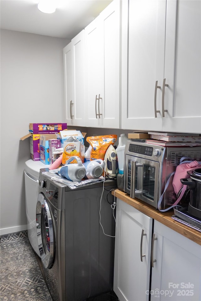 laundry room with cabinet space, baseboards, and washer and clothes dryer