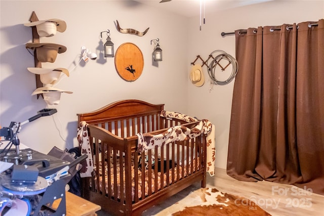 bedroom featuring a nursery area and wood finished floors