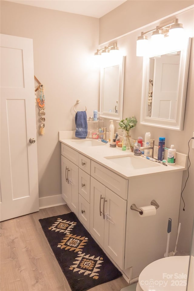 bathroom featuring toilet, wood finished floors, vanity, and baseboards