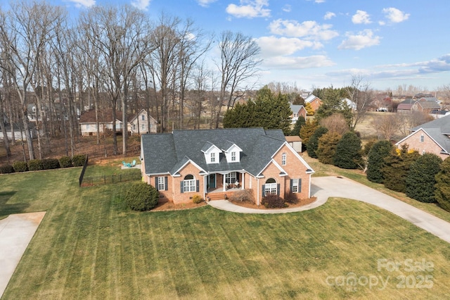 view of front of house featuring fence, a shingled roof, a front lawn, concrete driveway, and brick siding