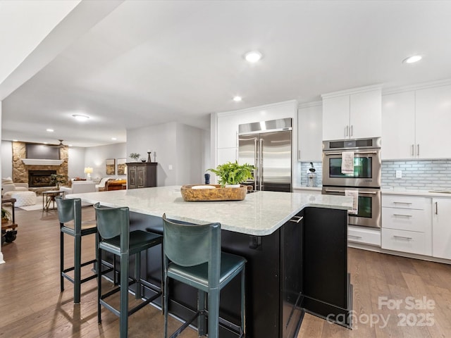 kitchen with appliances with stainless steel finishes, white cabinets, a kitchen island, and a kitchen bar