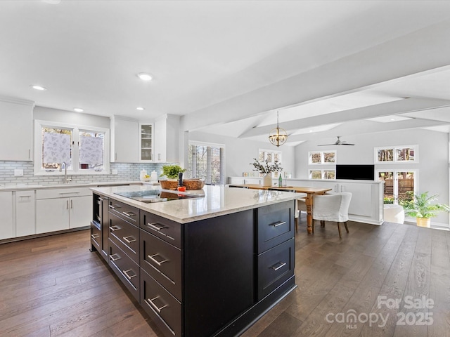 kitchen with tasteful backsplash, dark wood finished floors, glass insert cabinets, a center island, and white cabinetry