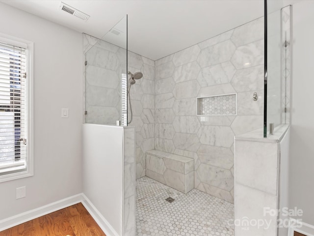 full bathroom featuring a walk in shower, visible vents, baseboards, and wood finished floors