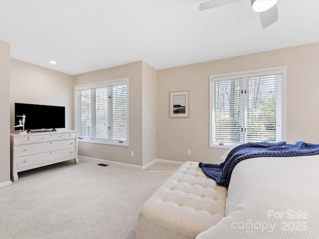 bedroom featuring visible vents, baseboards, a ceiling fan, and light colored carpet