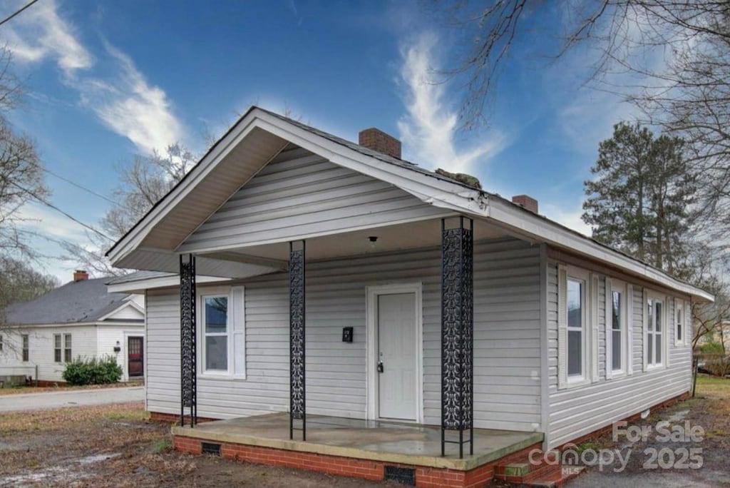 view of front of house featuring a porch, crawl space, and a chimney