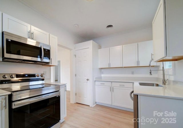 kitchen featuring a sink, stainless steel appliances, light countertops, and white cabinetry