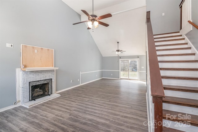 unfurnished living room with baseboards, a ceiling fan, stairway, wood finished floors, and a brick fireplace