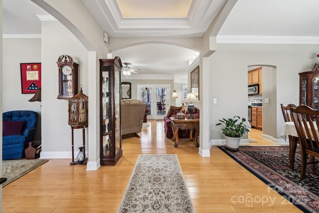 entryway with ornamental molding, baseboards, and light wood finished floors